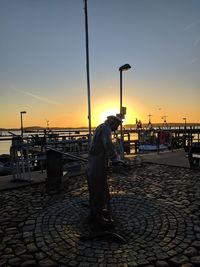 Man standing at harbor during sunset