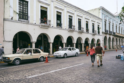 People on street against buildings in city