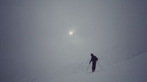 Full length of silhouette man skiing on snow against sky