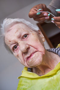 Elderly woman receiving facial hair removal from african american caregiver