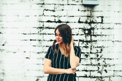Young woman standing against wall