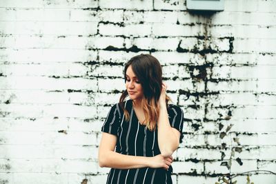 Young woman standing against white wall