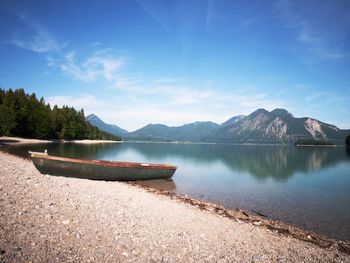 Fishing boat on shore on background of picturesque landscape of lake in bright sunny summer day.