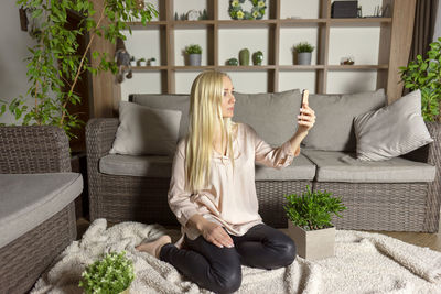 A blonde woman makes selfie on her mobile phone at home