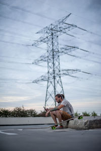 Boy posing with skateboard in hand and phone