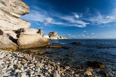 Rocks on sea shore against sky