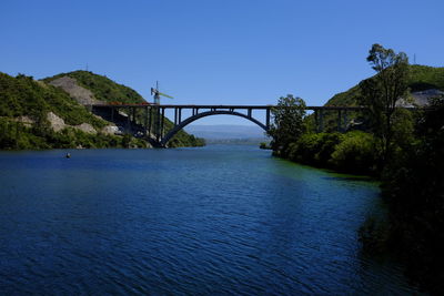 Bridge over river against clear blue sky