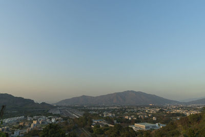 Aerial view of townscape and mountains against clear sky