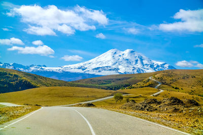 Road leading towards mountains against sky