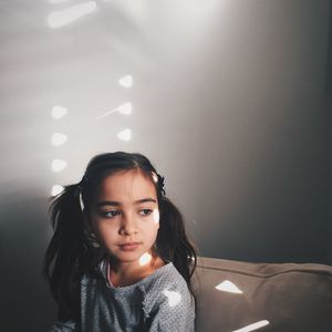 Girl looking away while sitting on couch