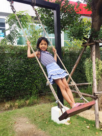 Portrait of smiling girl swinging in park