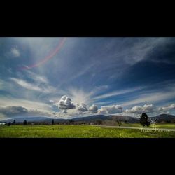 Scenic view of grassy field against cloudy sky