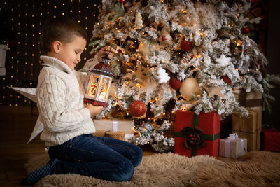 Full length of boy sitting in christmas tree