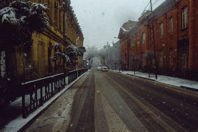 Wet street amidst buildings during winter