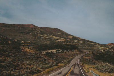 Road passing through mountain against sky