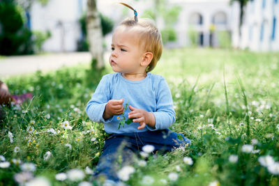 Cute girl looking away while sitting on grass