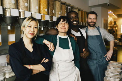 Portrait of multiracial male and female colleagues standing in food store