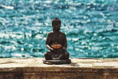 Statue of man sitting on retaining wall