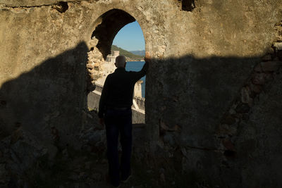 Rear view of man standing at arch window