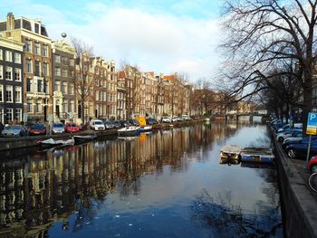 Boats moored in canal amidst buildings in city