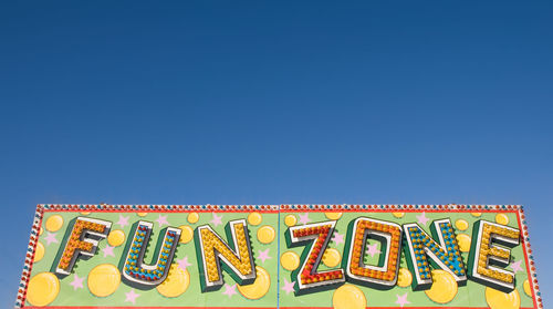 Low angle view of information sign against clear blue sky