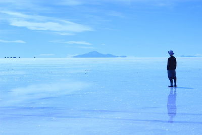 Rear view of man in sea against sky during winter