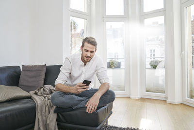 Man sitting on couch looking at cell phone