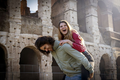 Young couple having fun traveling in rome. the man carries his girlfriend on his back.