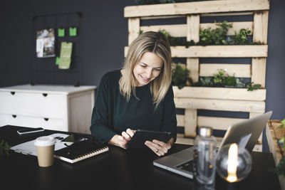 Young woman using phone while sitting on table