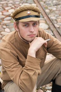 Portrait of young man in costume holding cigarette while sitting outdoors
