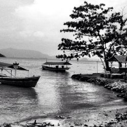 Boats in sea against cloudy sky