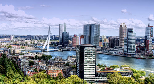 Modern buildings by river against sky in city