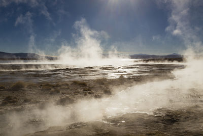 Smoke emitting from hot spring against blue sky