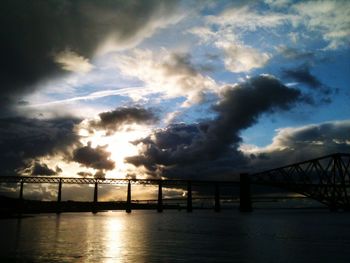 Bridge over river against cloudy sky