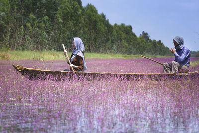 Rear view of people working on field against sky