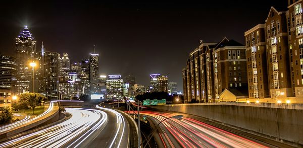 Light trails on highways amidst illuminated buildings at night