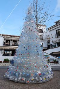 Christmas tree by building in city against sky