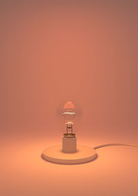 Close-up of light bulb against orange background