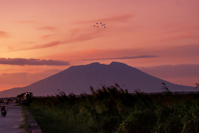 Scenic view of silhouette mountains against orange sky