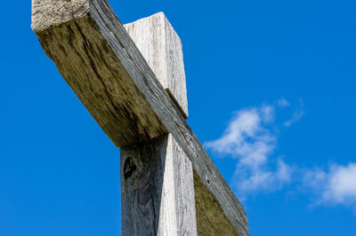 Low angle view of wooden post against blue sky