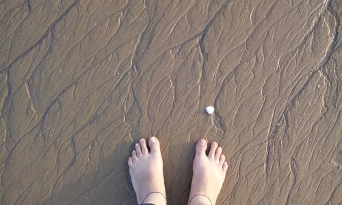 Low section of woman standing on beach