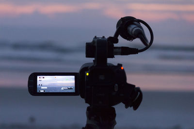 Close-up of home video camera at beach during sunset