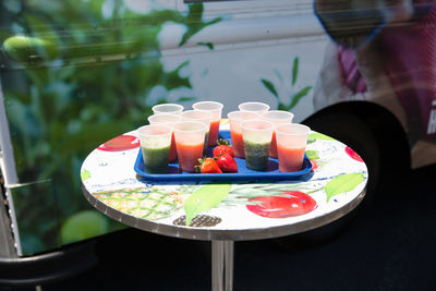 High angle view of smoothies in disposable glass by strawberries in tray at table