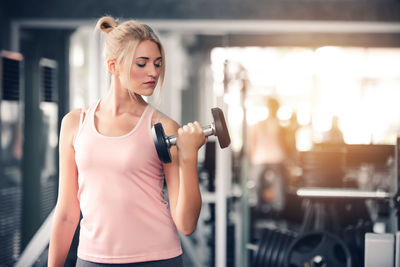 Young woman exercising with dumbbells in gym