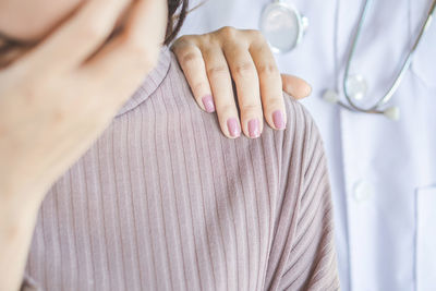 Midsection of doctor consoling woman in hospital