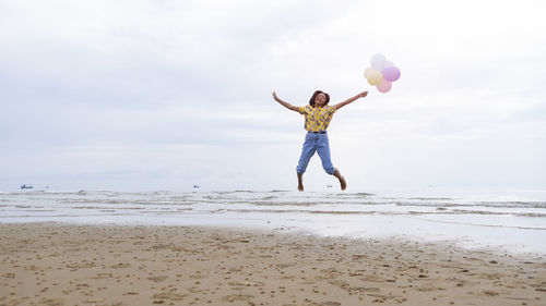 Full length of man with umbrella at beach against sky