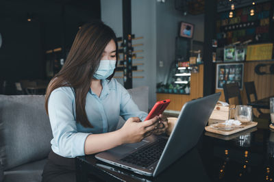 Midsection of woman using mobile phone while sitting on table