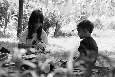 Siblings playing with toys while sitting on grass