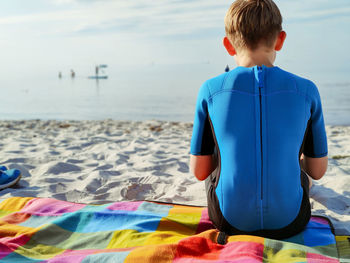 Rear view of boy sitting on beach