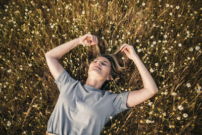 Woman with hands in hair lying on field